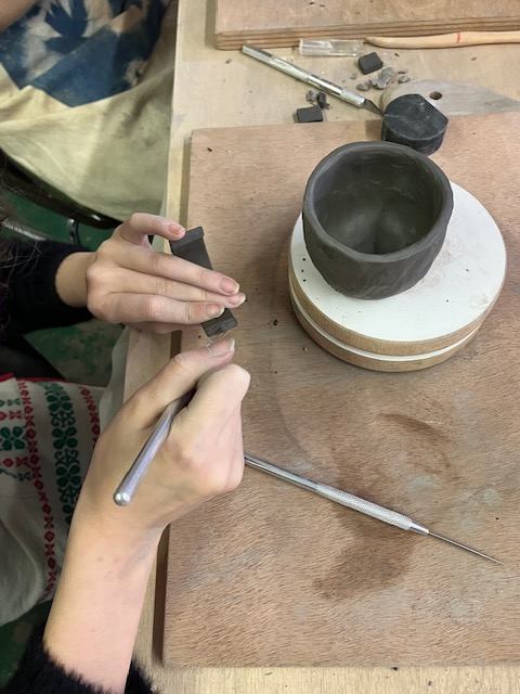 mains qui modèlent une tasse en céramique